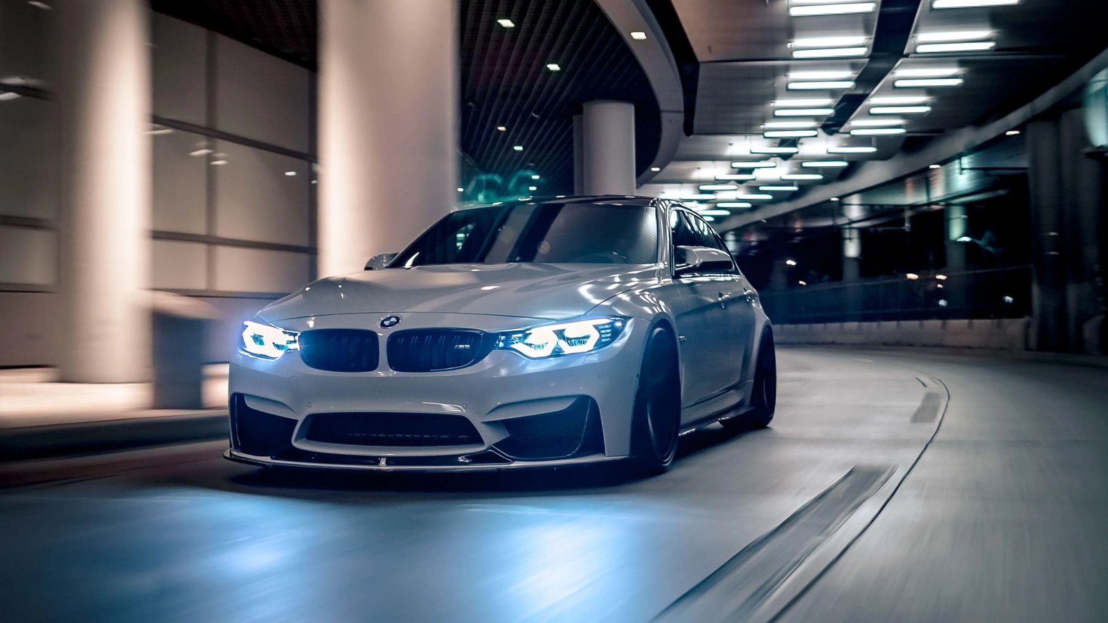 BMW M3 blanche de nuit dans un parking souterrain